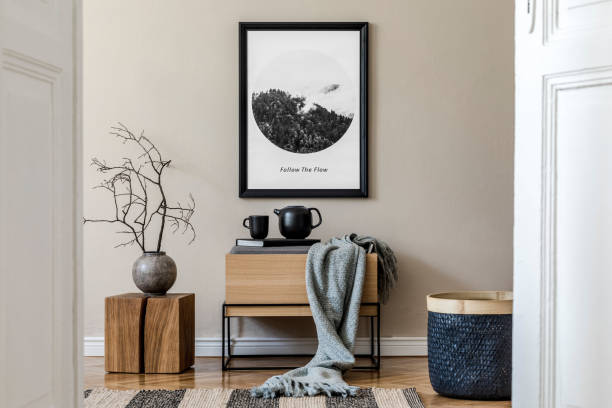 istock Modern scandinavian living room interior with black mock up poster frame, design commode, leaf in vase, black rattan basket, books and elegant accessories. Template. Stylish home decor. 1190168937
