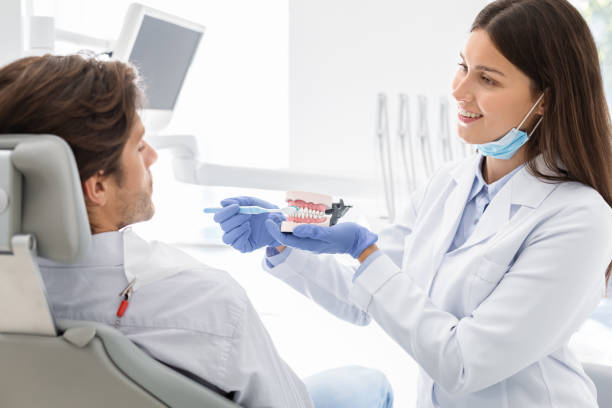 istock Beautiful dentist showing how to brush teeth on jaw model 1190168953
