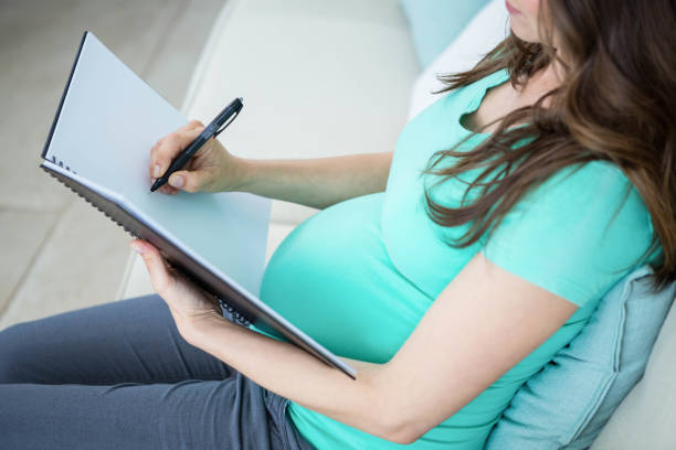 istock Pregnant woman writing on document 1190169004