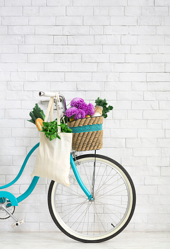 Clean the planet. Retro bike with wildflowers and organic vegetables over white bricks wall background, copy space