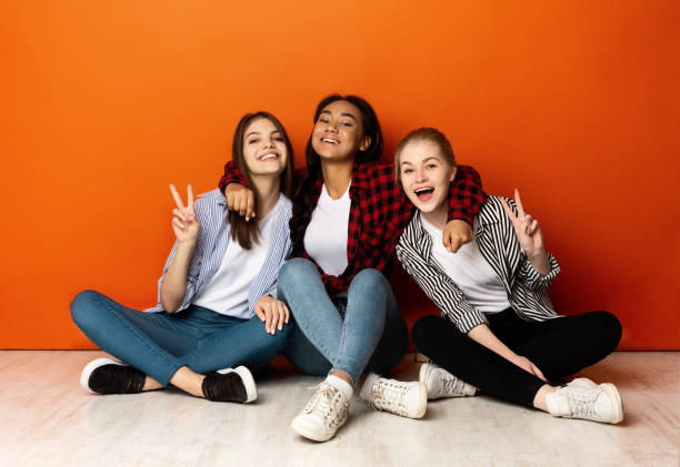 istock Positive girlfriends smiling to camera and showing peace gestures 1190170411