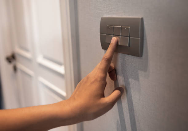 istock Asian female right hand is turning off on grey light switch. 1190170415