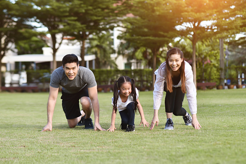 Asian family exercising at park outdoor. Mother, Father, Daughter getting ready to start on grass for running.