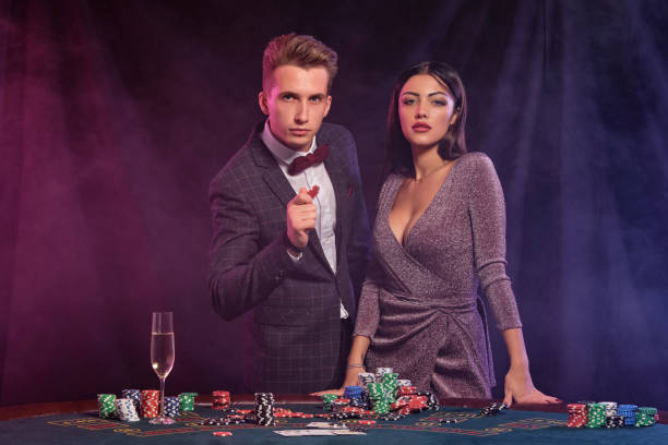 mężczyzna i kobieta grający w pokera w kasynie, świętując wygraną przy stole ze stosami żetonów, pieniędzy, kart, szampana. czarny, tło dymu. zbliżenie - casino black and white gambling chip gambling zdjęcia i obrazy z banku zdjęć