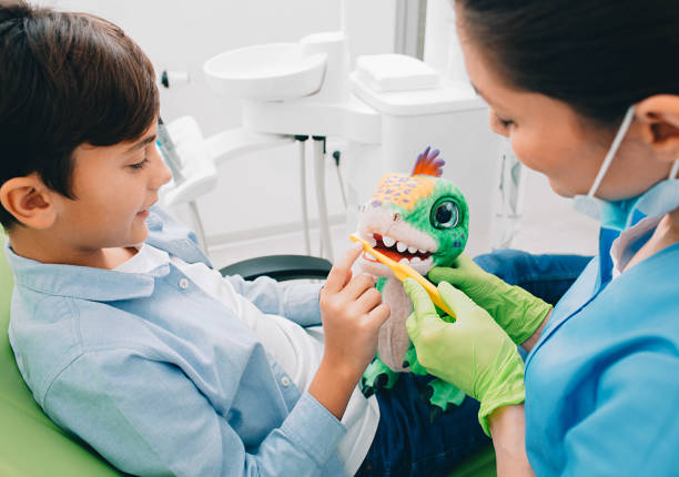 istock Boy with dentist having fun with toy. Dentist talking how clean teeth with toothbrush 1190177280