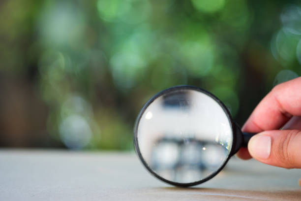 Man hand holding the magnifying glass with nature background