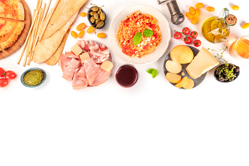 Italian food. Pizza, pasta, cheese, hams, olives and olive oil, shot from above on a white background with copy space, a flat lay composition