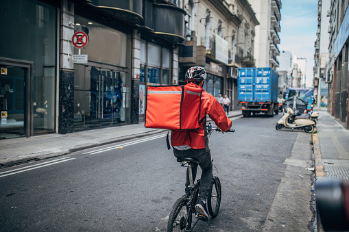 Delivery boy on bicycle in city