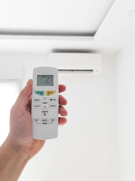 istock Modern air conditioner unit with a hand holding a remote. 1190181501