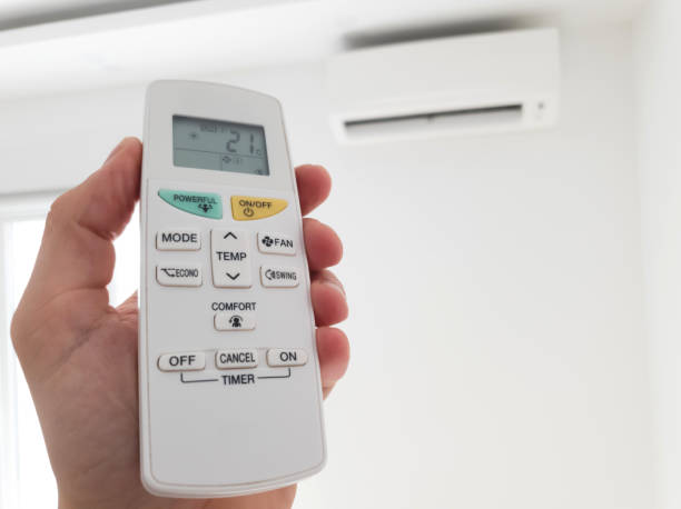 istock Modern air conditioner unit with a hand holding a remote. 1190181530