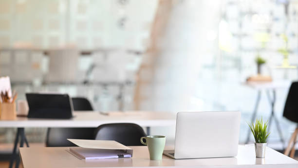 istock Contemporary business workspace with laptop, document file, plant and coffee mug on white able. 1190185069