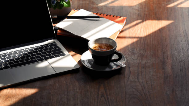 istock Tea cup on workspace table with laptop, notebook with pencil at morning time. 1190185283