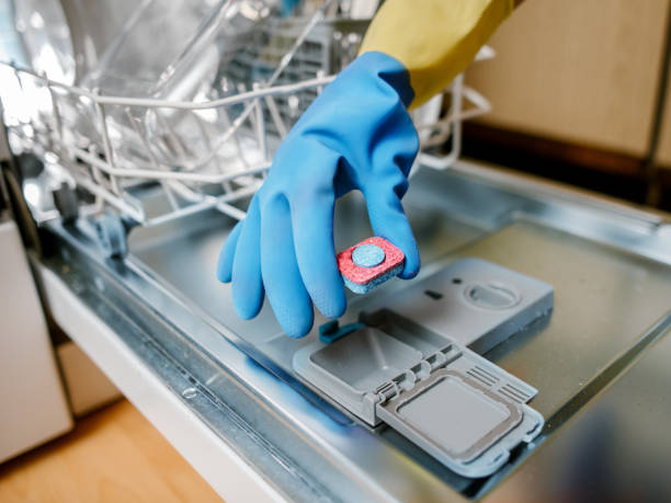 kobieta wkładająca tabletkę do pudełka z detergentem do zmywarki - dishwashing detergent zdjęcia i obrazy z banku zdjęć