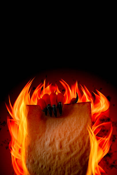 Pact to sell your soul to Lucifer, strike a Faustian bargain or deal with the devil concept theme with Satan holding in creepy ugly red hand with pointy claws a blank burning scroll with copy space pacto para vender su alma a lucifer, golpear un acuerdo faustino o lidiar con el tema concepto del diablo con satanás sosteniendo en la mano roja fea espeluznante con garras puntiagudos un pergamino en llamas en blanco con espacio de copia