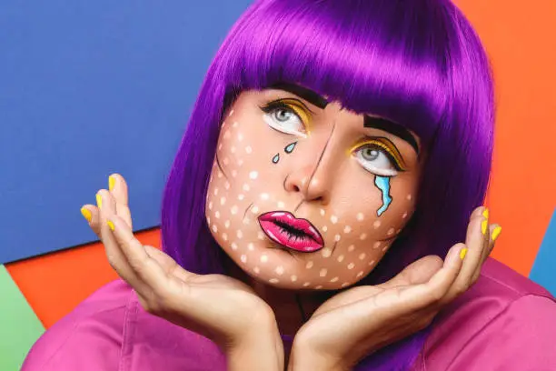 Model in creative image with pop art makeup against colorful background