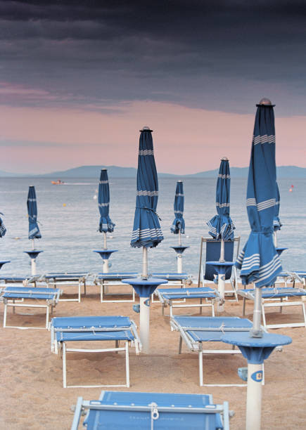 istock Row of closed beach umbrellas and folded deck chairs 1190204718