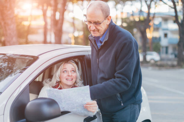 bella donna di mezza età che chiede la strada dal passante - vecchio che mostra il posto sulla mappa - viaggio, trasporto e motivo del concetto di appuntamenti - driving senior adult car women foto e immagini stock