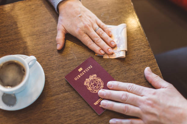 Male and female hands with passport and money on the table - concept of illegal immigration, sale of fake passports, sham (fake) marriage stock photo