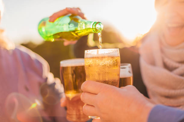 gruppo di amici felici che bevono birra e si divertono - giovane ragazza sorridente che versa birra dalla bottiglia verde - irish culture beer drinking pub foto e immagini stock