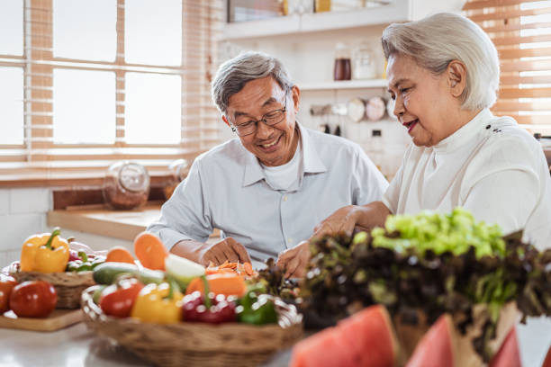 senior asian couple cooking together in kitchen - cooking senior adult healthy lifestyle couple imagens e fotografias de stock