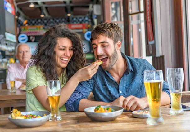 istock Young couple flirting at pub drinking beer and eating 1190206423