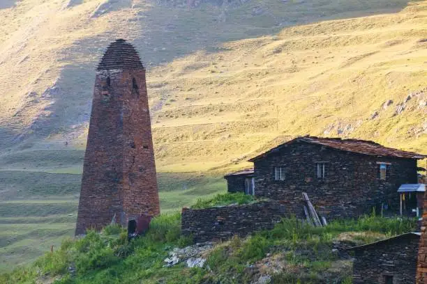 Photo of Scenic landscape of summer morning in the Caucasus mountains. Sun just came out and illuminates ancient ruins of Tushetian defensive towers. Trekking from Omalo to Shatili, Atsunta Pass, Georgia