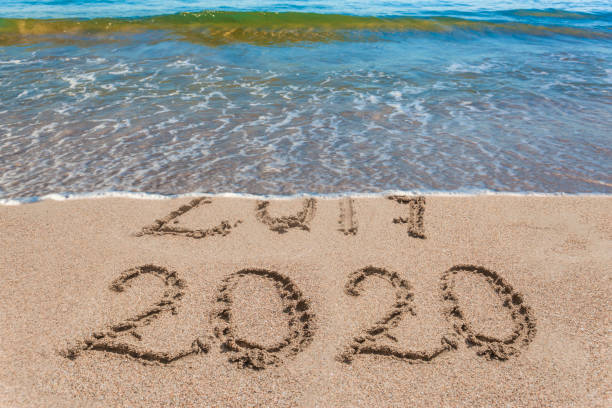 istock New year 2020 and 2019 on sandy beach with waves 1190208327