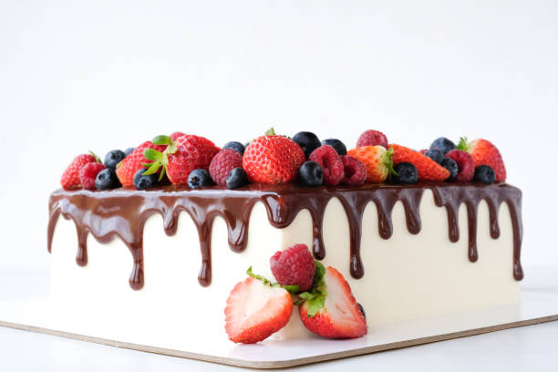 istock Square cake on birthday decorated with fresh berries, poured with chocolate on a white background. 1190208349