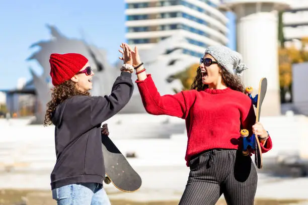 Photo of Two teen skaters bumping their hands on the streets of Barcelona