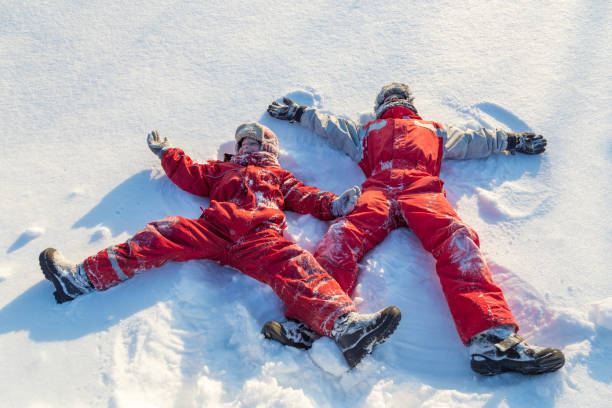 istock Two boys in winter clothes making snow angel 1190214083
