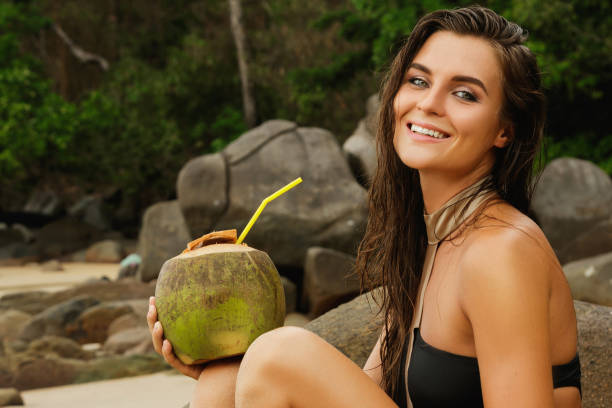 istock Happy woman with a coconut drink on the beach 1190214375