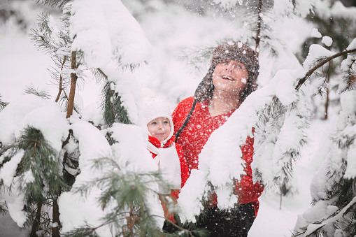Portrait of happy little girl in red coat with dad having fun with snow in winter forest. girl playing with dad