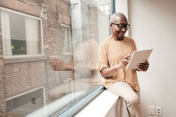 istock Senior woman with tablet near window 1190216788