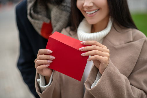 Romantic letter. Close up of a red envelope being opened while having a love letter inside