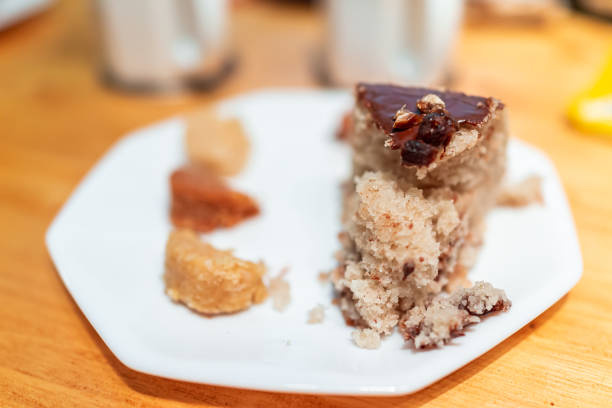 primer plano de rebanada de postre amarillo de vainilla pastel de esponja casero con glaseado de chocolate y macarrones de coco en la mesa - almond macaroon fotografías e imágenes de stock