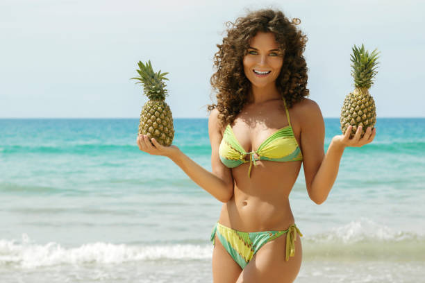 istock Woman with a pineapplel on the beach 1190223012