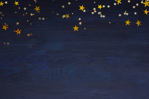 Dark-blue wooden background with golden stars with copy space for text.