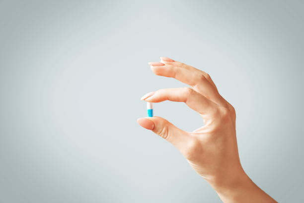 istock Female hand holding a capsule pill or vitamin. 1190224574
