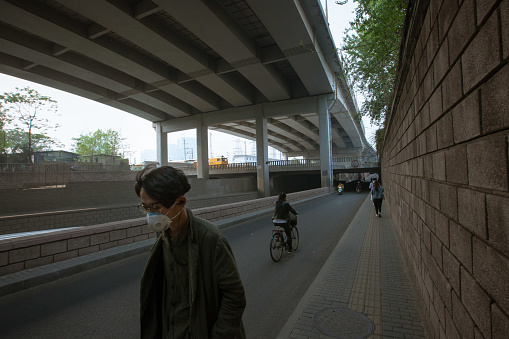 Utilitarian Beijing modern architecture. Man walking with anti pollution mask.