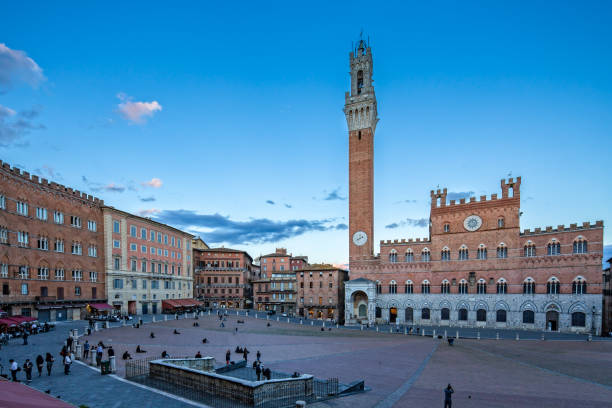 Tourists enjoying the sunset at Piazza del Campo The Palazzo Pubblico - Town Hall - in Siena is an imposing sight in the Piazza del Campo and is considered together with the Torre del Mangia as one of the most important symbols of the city, Tuscany, Italy facade store old built structure stock pictures, royalty-free photos & images