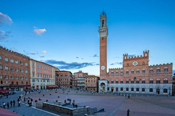 Tourists enjoying the sunset at Piazza del Campo The Palazzo Pubblico - Town Hall - in Siena is an imposing sight in the Piazza del Campo and is considered together with the Torre del Mangia as one of the most important symbols of the city, Tuscany, Italy torre del mangia stock pictures, royalty-free photos & images