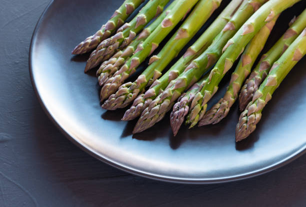 istock Plate of fresh asparagus on rustic black background 1190229527