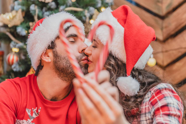 nahaufnahme porträt von amourösen küssen paar hält ein süßigkeiten herz auf verschwommenen vordergrund. - sex symbol couple kissing women stock-fotos und bilder