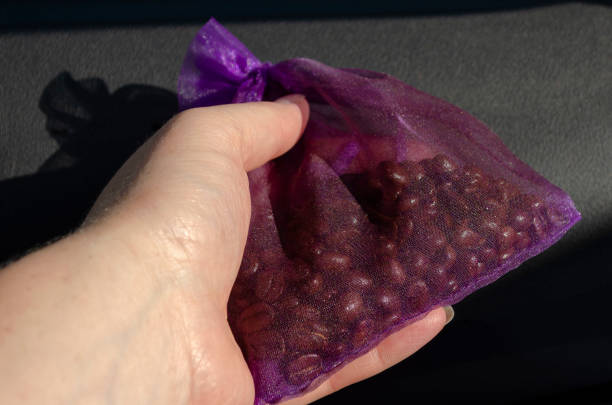 Female hand holds a purple nylon bag with coffee grains