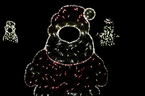 Christmas red and white night lights simulating shape of frozen snowman. Street city New Year and Christmas decorations, string rice lights bulbs. Ornaments to christmas celebration, holiday scene.