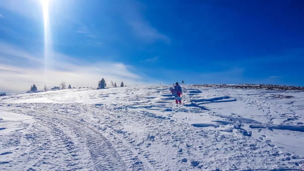 Bad Kleinkirchheim - A girl having fun in the snow with beautiful view A girl with a snowboard in her hand walking on a powder snow in Bad Kleinkirchheim, Austria. There are few traits on the snow. Massive ski resort in Alps. Perfect weather for skiing. Winter sports. snowboarding snowboard women snow stock pictures, royalty-free photos & images