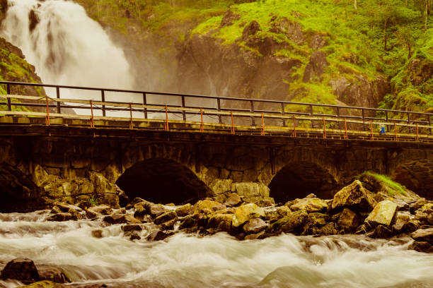 Norwegian landscape. Waterfall Latefoss Latefossen with stone arched bridge road, Odda Hordaland Norway. National tourist Hardanger road 13.