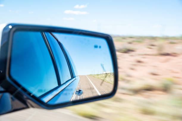 Driving on a highway in the US desert. Freeway reflected in a car wing mirror in a spring day, blur desert background