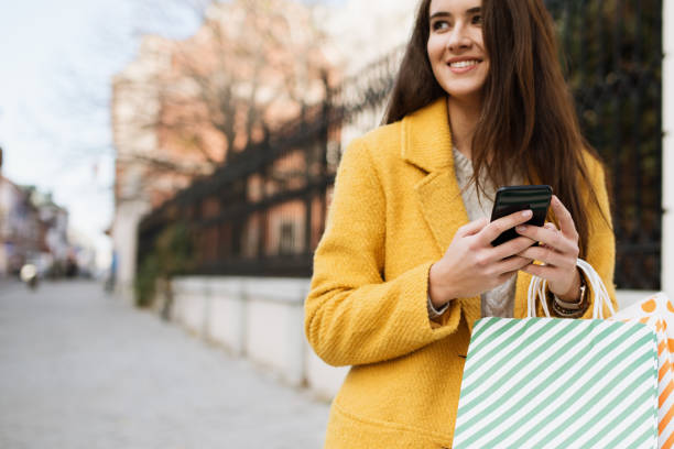 istock Woman in a yellow coat using mobile 1190245108