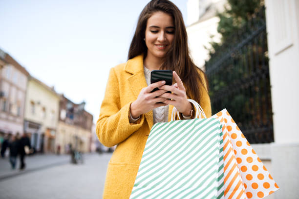 istock Woman in a yellow coat using mobile 1190245120